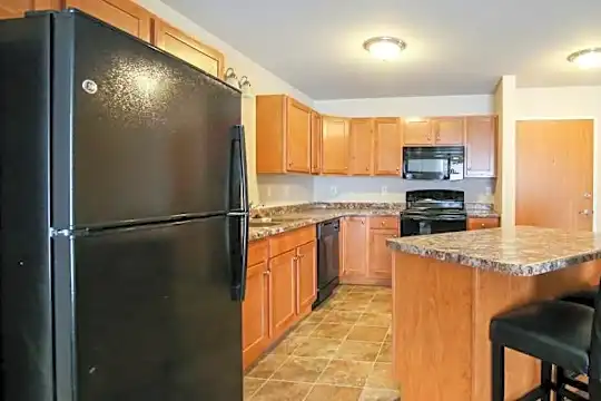 kitchen with a kitchen breakfast bar, refrigerator, dishwasher, range oven, microwave, light granite-like countertops, light tile floors, and brown cabinets