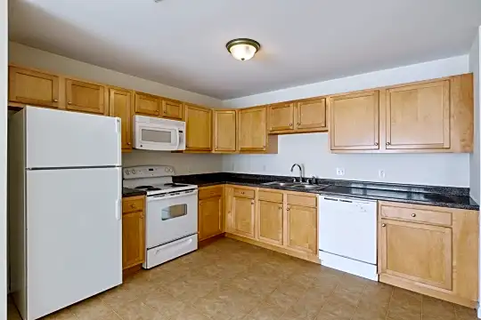 kitchen featuring refrigerator, electric range oven, dishwasher, microwave, dark countertops, light tile floors, and brown cabinets
