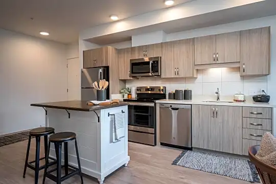 kitchen featuring a kitchen island, a breakfast bar, stainless steel appliances, electric range oven, light brown cabinets, and light hardwood floors