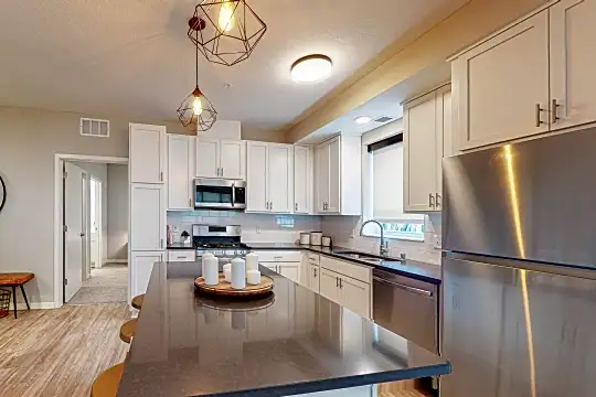 kitchen with stainless steel appliances, range oven, white cabinetry, light hardwood flooring, dark countertops, and pendant lighting