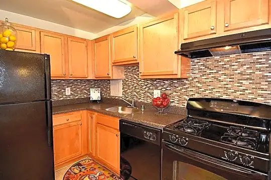 kitchen with ventilation hood, refrigerator, dishwasher, gas range oven, light floors, dark granite-like countertops, and light brown cabinetry