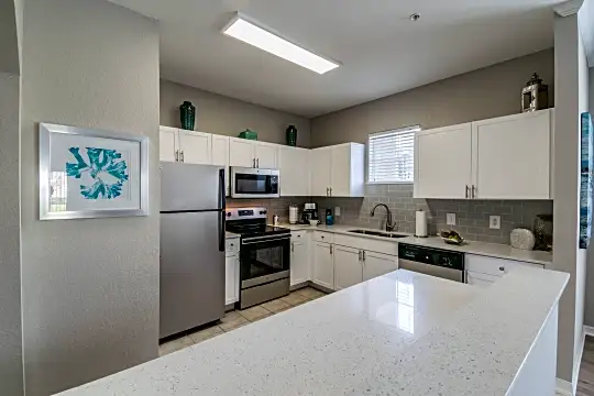 kitchen featuring natural light, refrigerator, dishwasher, electric range oven, stainless steel microwave, light floors, white cabinets, and light countertops