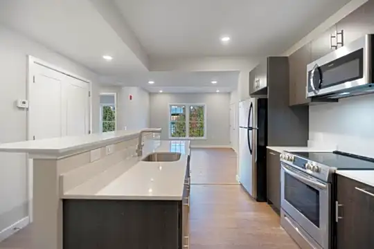 kitchen with a kitchen island, natural light, stainless steel microwave, refrigerator, electric range oven, light countertops, dark brown cabinets, and light parquet floors