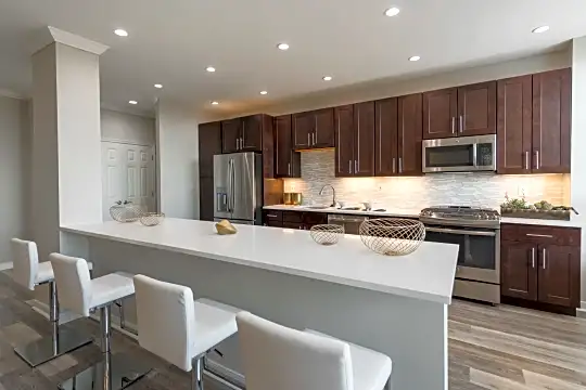 kitchen featuring range oven, stainless steel appliances, light countertops, kitchen island sink, dark brown cabinetry, and dark hardwood flooring