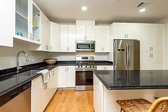 kitchen with gas range oven, stainless steel appliances, dark countertops, white cabinetry, and light hardwood flooring