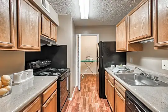 kitchen with ventilation hood, refrigerator, electric range oven, dishwasher, light countertops, brown cabinets, and light hardwood flooring