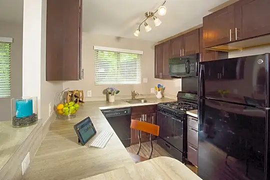 kitchen featuring a healthy amount of sunlight, refrigerator, gas range oven, dishwasher, microwave, light countertops, and dark brown cabinets