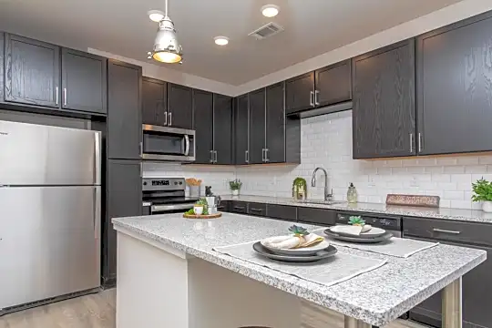 kitchen with a center island, stainless steel appliances, range oven, light hardwood floors, pendant lighting, light granite-like countertops, and dark brown cabinets