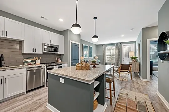 kitchen with a kitchen island, stainless steel appliances, range oven, white cabinets, light granite-like countertops, pendant lighting, and light hardwood flooring