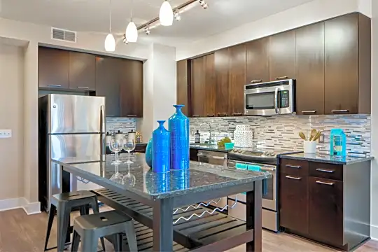 kitchen featuring range oven, stainless steel appliances, dark brown cabinets, pendant lighting, light hardwood floors, and dark stone countertops