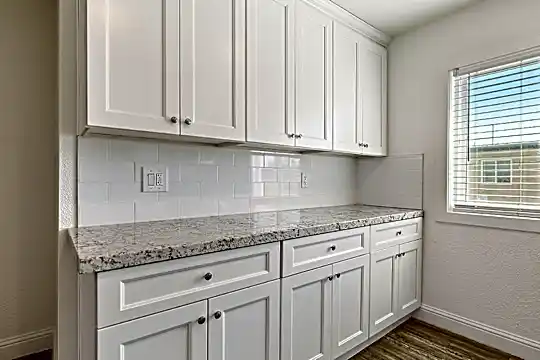 kitchen featuring natural light, granite-like countertops, white cabinetry, and dark hardwood floors
