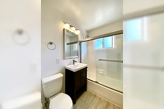 full bathroom featuring hardwood floors, natural light, oversized vanity, mirror, toilet, and enclosed tub / shower combo