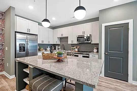 kitchen featuring stainless steel appliances, range oven, light countertops, pendant lighting, light hardwood floors, and white cabinetry