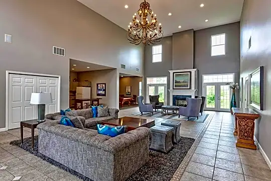 living room featuring a high ceiling, a notable chandelier, a fireplace, a wealth of natural light, tile flooring, and refrigerator