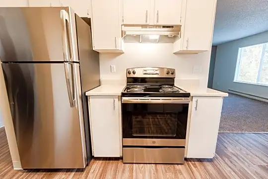 kitchen with natural light, electric range oven, stainless steel refrigerator, baseboard radiator, fume extractor, white cabinets, light countertops, and light parquet floors
