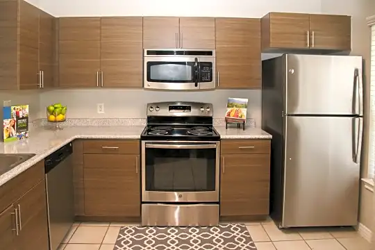 kitchen with electric range oven, stainless steel appliances, light flooring, dark brown cabinetry, and light countertops