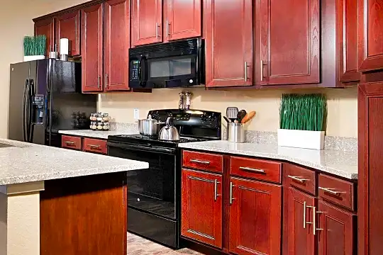 kitchen featuring refrigerator, electric range oven, microwave, light flooring, light granite-like countertops, and dark brown cabinets