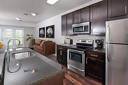 kitchen with natural light, stainless steel appliances, electric range oven, dark hardwood flooring, dark granite-like countertops, and dark brown cabinets