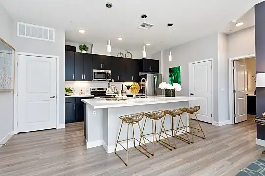 kitchen featuring a kitchen bar, stainless steel appliances, range oven, dark brown cabinets, light hardwood flooring, pendant lighting, and light countertops