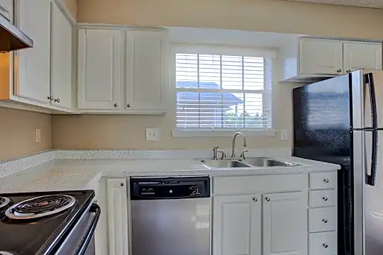 kitchen featuring natural light, refrigerator, stainless steel dishwasher, exhaust hood, white cabinets, and light countertops