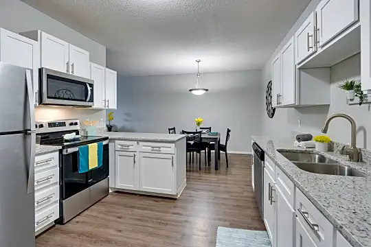 kitchen with stainless steel microwave, refrigerator, electric range oven, dishwasher, white cabinetry, light granite-like countertops, pendant lighting, and light hardwood flooring