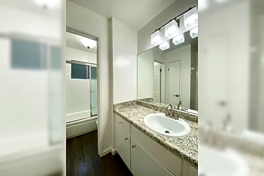 bathroom with parquet floors, vanity, mirror, and enclosed tub / shower combo