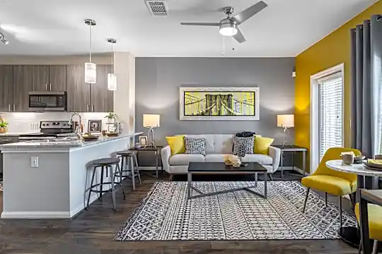 hardwood floored living room with a ceiling fan, a breakfast bar area, natural light, range oven, and microwave