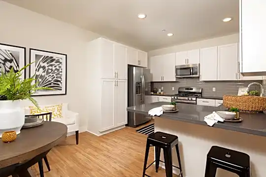 kitchen with a kitchen breakfast bar, stainless steel appliances, gas range oven, dark countertops, white cabinetry, and light parquet floors