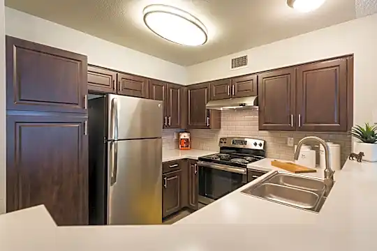 kitchen with electric range oven, stainless steel refrigerator, fume extractor, dark brown cabinetry, and light countertops