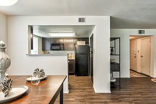 kitchen with refrigerator, microwave, dark brown cabinetry, dark countertops, and dark hardwood floors