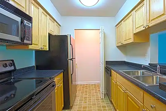 kitchen with stainless steel microwave, refrigerator, dishwasher, dark granite-like countertops, light tile flooring, and brown cabinets