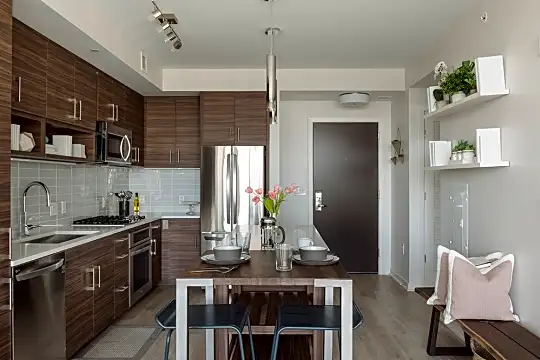 kitchen featuring gas cooktop, oven, dishwasher, stainless steel refrigerator, microwave, dark brown cabinetry, light countertops, pendant lighting, and light hardwood flooring