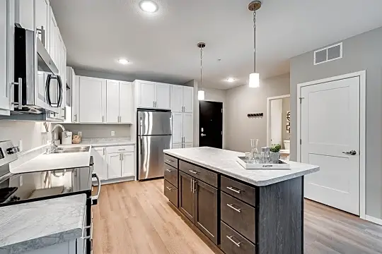kitchen featuring a center island, stainless steel refrigerator, electric range oven, microwave, pendant lighting, light stone countertops, light parquet floors, and white cabinets
