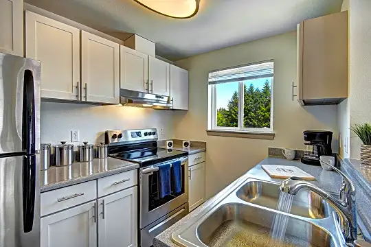kitchen featuring natural light, stainless steel refrigerator, electric range oven, extractor fan, white cabinetry, and light stone countertops