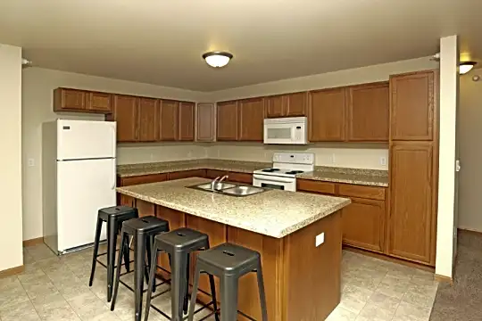 kitchen with refrigerator, electric range oven, microwave, light granite-like countertops, light tile flooring, and brown cabinets