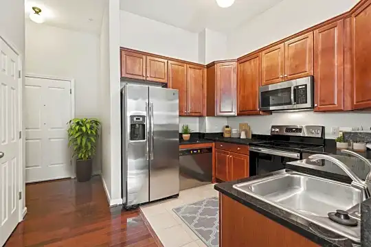 kitchen with electric range oven, stainless steel appliances, dark brown cabinets, dark hardwood floors, and dark countertops