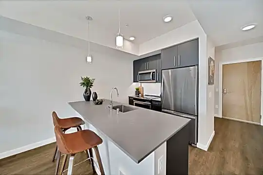kitchen with a breakfast bar, a kitchen island, stainless steel appliances, range oven, dark brown cabinetry, light countertops, pendant lighting, and dark hardwood floors