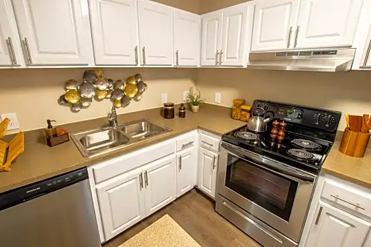 kitchen with electric range oven, stainless steel dishwasher, range hood, white cabinets, light countertops, and light hardwood floors