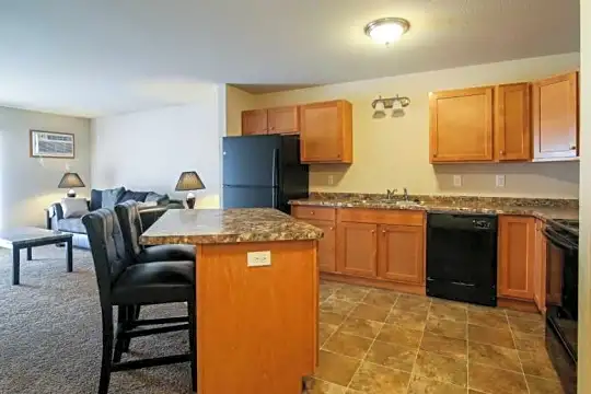 kitchen featuring a breakfast bar, refrigerator, dishwasher, range oven, dark tile flooring, dark granite-like countertops, and brown cabinets