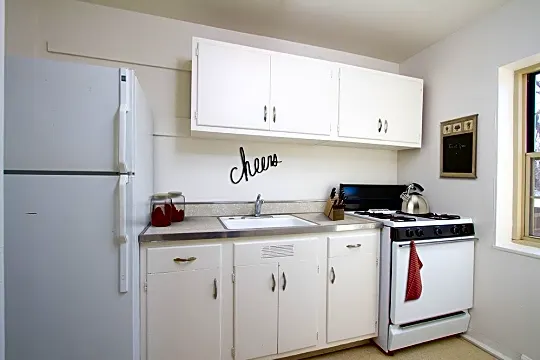 kitchen with gas range oven, refrigerator, light floors, white cabinets, and light countertops