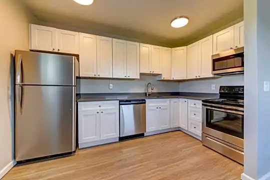 kitchen with stainless steel appliances, electric range oven, dark countertops, light parquet floors, and white cabinets