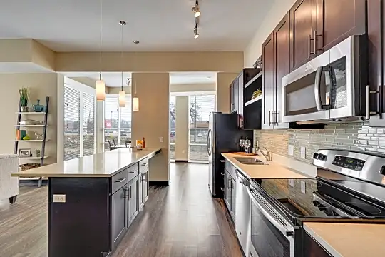 kitchen featuring a kitchen island, plenty of natural light, electric range oven, dishwasher, microwave, dark brown cabinets, pendant lighting, light parquet floors, and light countertops