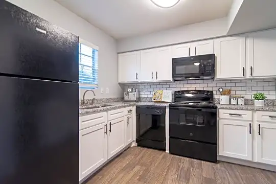 kitchen featuring natural light, refrigerator, electric range oven, dishwasher, microwave, light countertops, white cabinetry, and light parquet floors