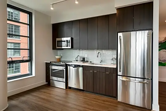 kitchen with natural light, stainless steel appliances, range oven, dark hardwood flooring, dark brown cabinets, and light countertops