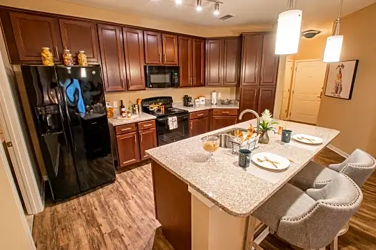 kitchen featuring refrigerator, electric range oven, microwave, pendant lighting, light hardwood floors, light stone countertops, and dark brown cabinets