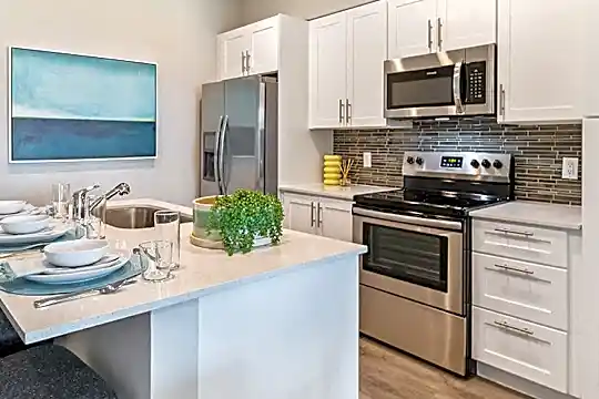 kitchen featuring a kitchen breakfast bar, stainless steel appliances, electric range oven, white cabinets, light parquet floors, and light countertops