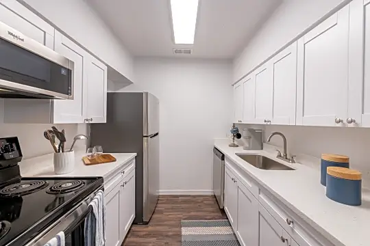 kitchen featuring refrigerator, dishwasher, microwave, white cabinets, light countertops, and dark hardwood flooring