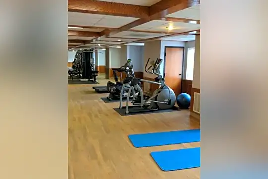 gym with hardwood floors and beamed ceiling