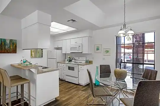 kitchen featuring plenty of natural light, skylight, a kitchen bar, refrigerator, electric range oven, microwave, white cabinetry, dark hardwood floors, pendant lighting, and light countertops