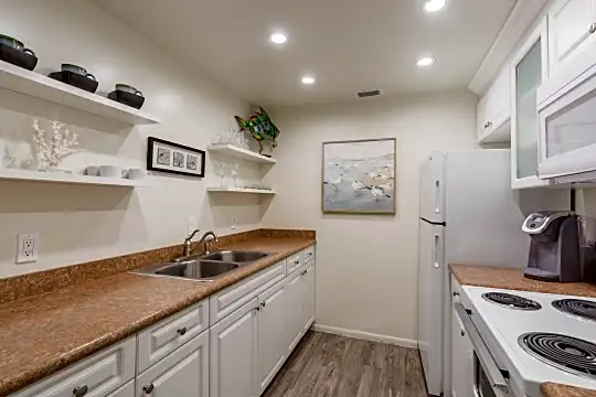 kitchen with refrigerator, microwave, white cabinets, light countertops, and light parquet floors